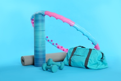 Photo of Hula hoop, yoga mats, gym bag and dumbbells on light blue background