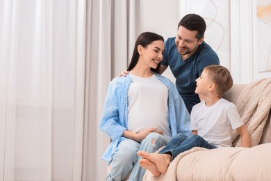 Photo of Pregnant woman spending time with her son and husband at home, space for text. Happy family