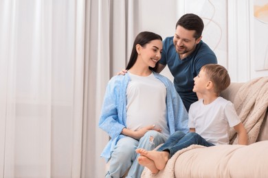 Pregnant woman spending time with her son and husband at home, space for text. Happy family