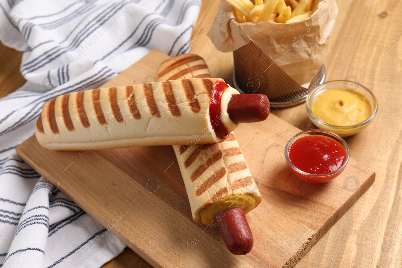 Photo of Delicious french hot dog, fries and dip sauces on wooden table