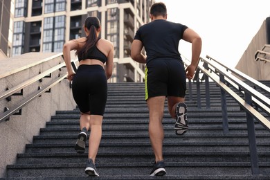 Healthy lifestyle. Couple running up steps outdoors, low angle view