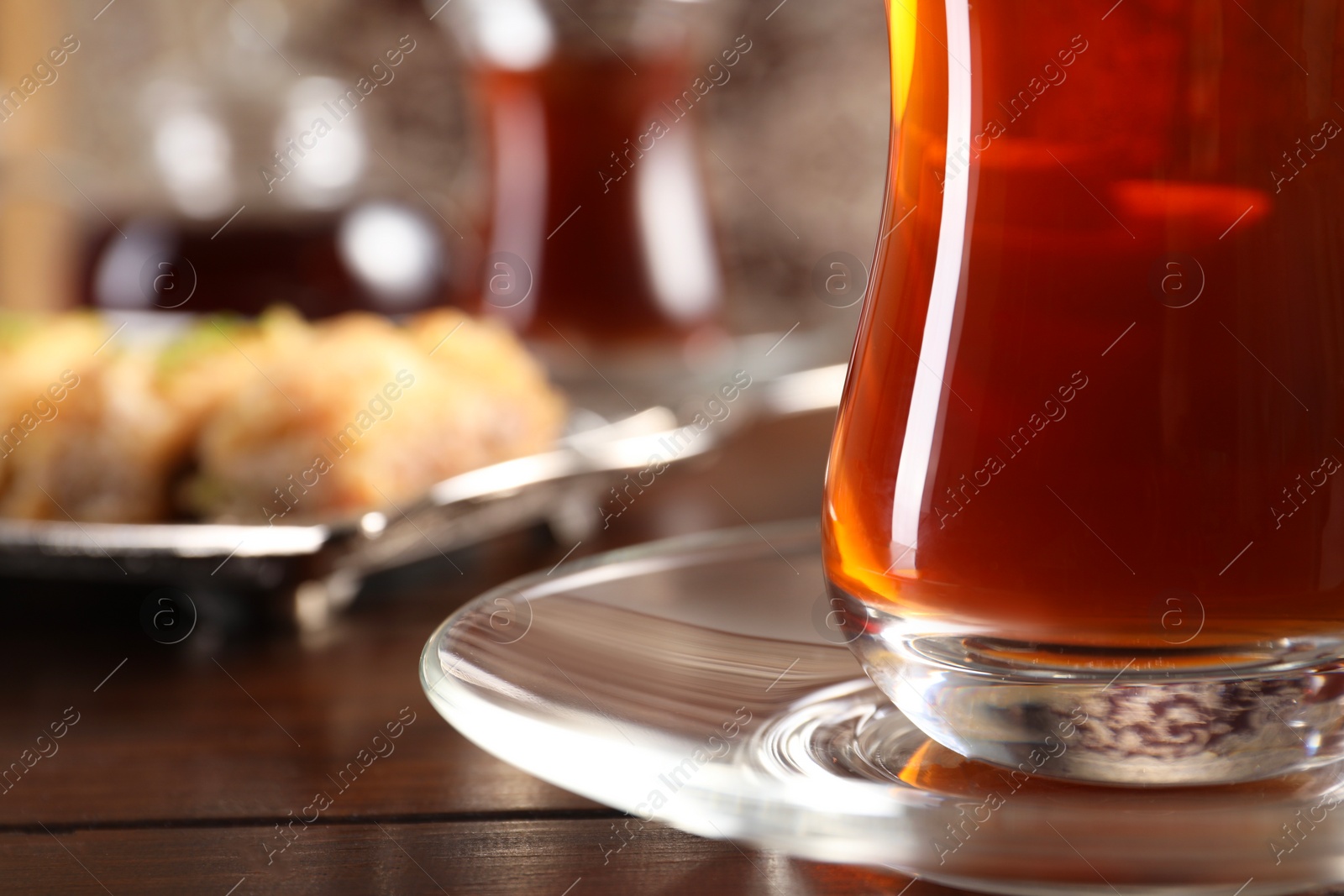 Photo of Traditional Turkish tea in glass on wooden table, closeup. Space for text