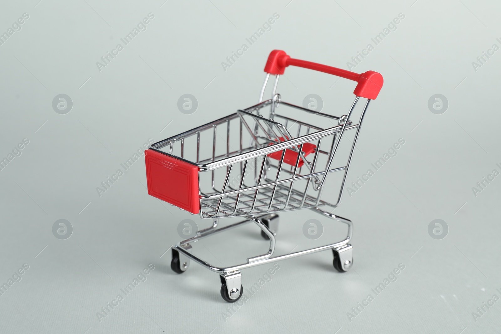 Photo of Small metal shopping cart on light background