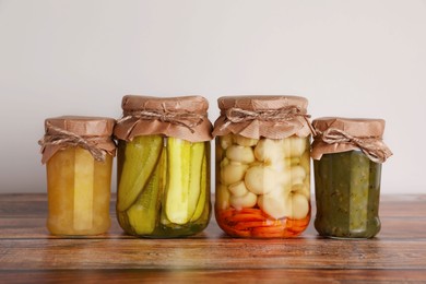 Jars with different preserved ingredients on wooden table