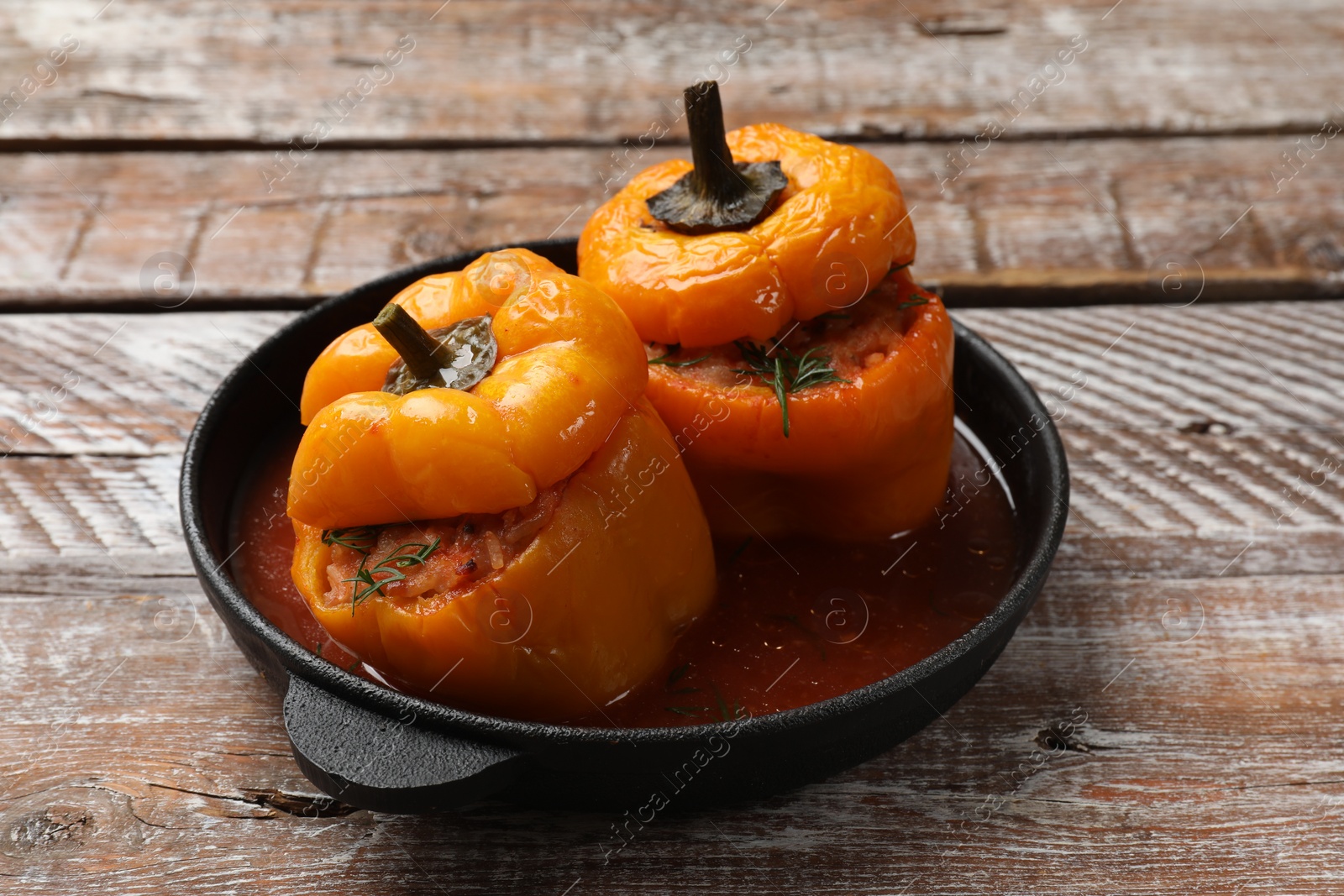 Photo of Tasty stuffed peppers in pan on wooden rustic table, closeup