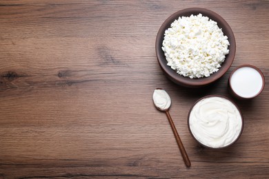 Clay dishware with fresh dairy products on wooden table, flat lay. Space for text