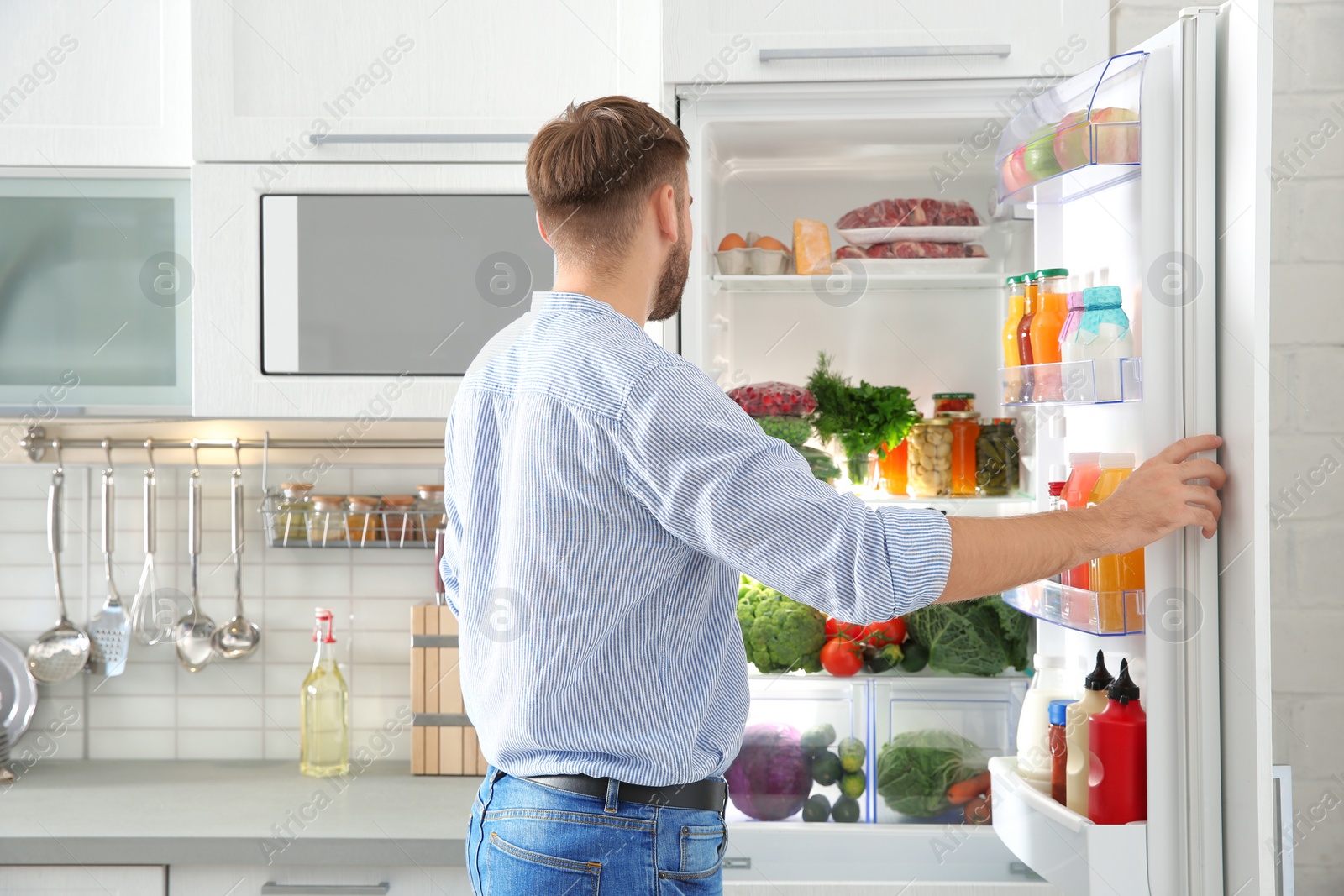 Photo of Man choosing food from refrigerator in kitchen