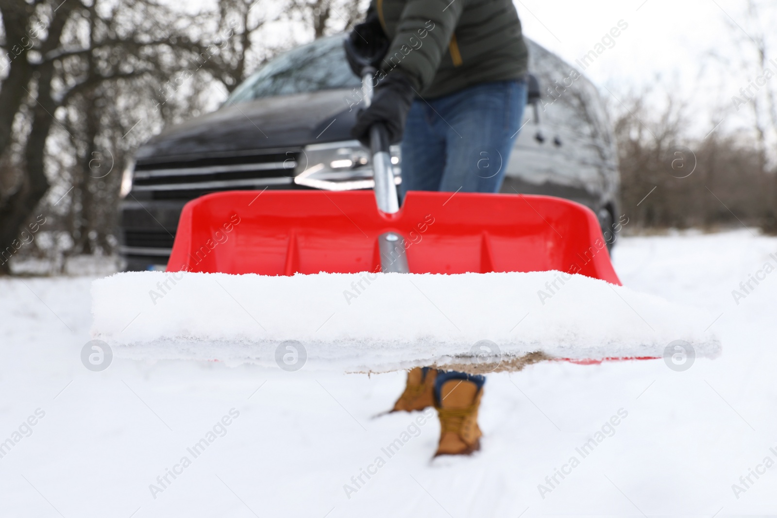 Photo of Man removing snow with shovel near car outdoors on winter day, closeup