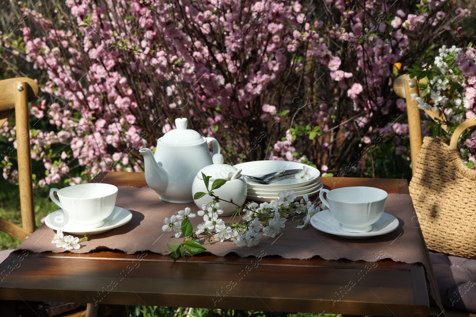 Photo of Beautiful spring flowers on table served for tea drinking in garden