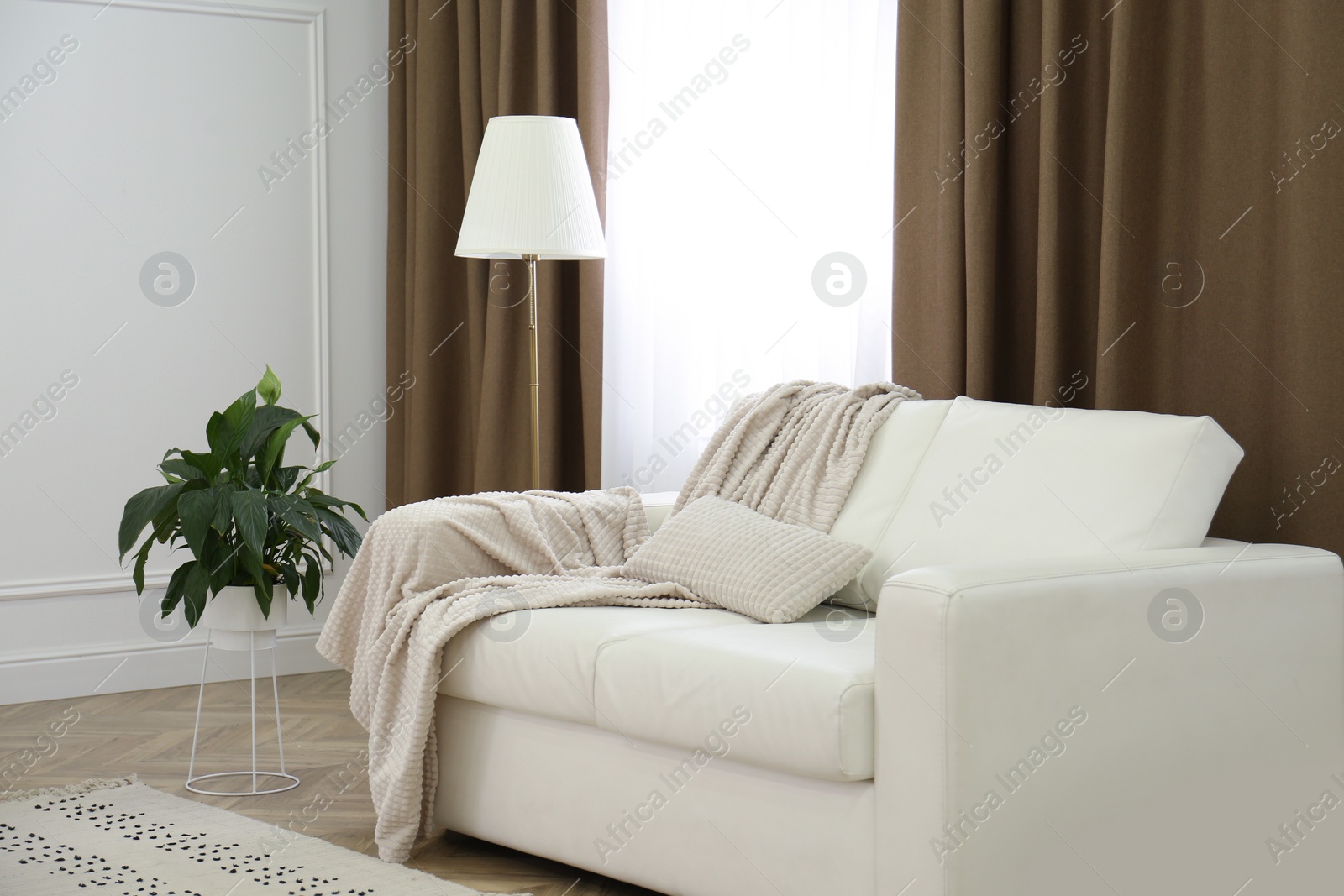 Photo of Sofa and window with brown curtains in simple room interior