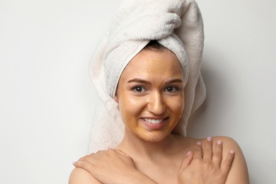 Beautiful woman with mask on face against light background