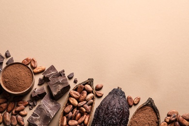 Flat lay composition with cocoa pods and chocolate on beige background, space for text