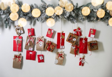 Photo of Christmas Advent calendar with gifts and decor hanging on light wall