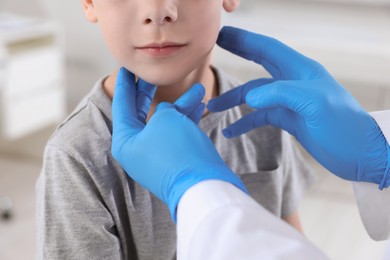 Endocrinologist examining boy's thyroid gland at hospital, closeup