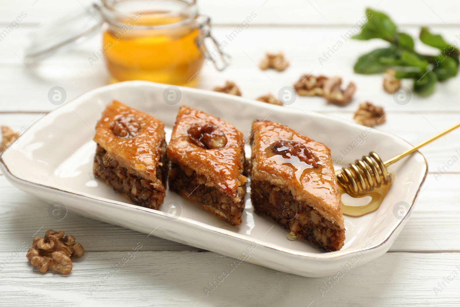 Photo of Delicious sweet baklava with walnuts on white wooden table