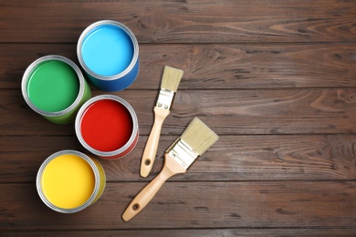 Flat lay composition with paint cans and brushes on wooden background. Space for text