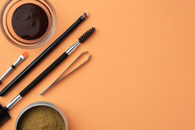 Photo of Flat lay composition with eyebrow henna and professional tools on orange background, space for text