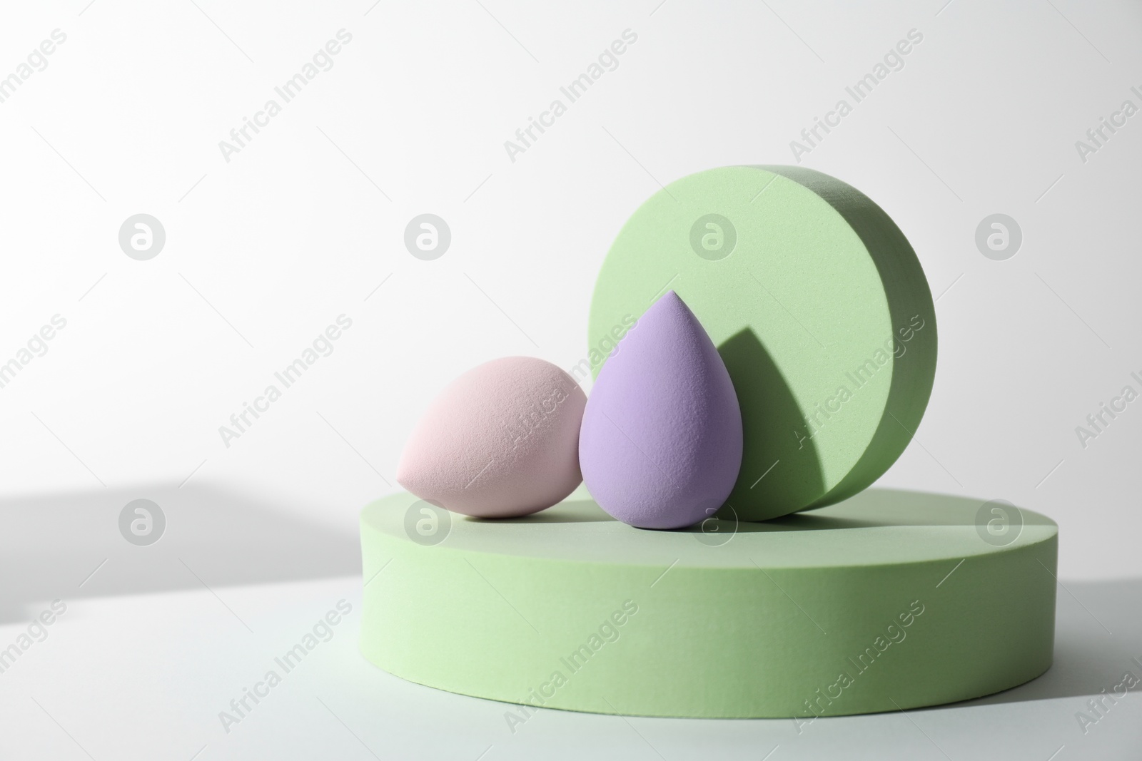 Photo of Stylish presentation of color makeup sponges on white background, space for text