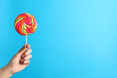 Woman holding yummy candy on color background. Space for text