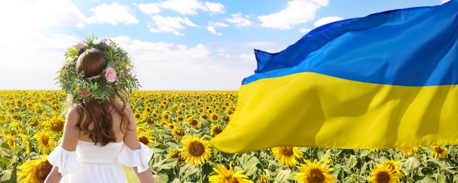 Pray for Ukraine. Ukrainian flag waving near young woman with flower wreath in sunflower field on sunny day, banner design