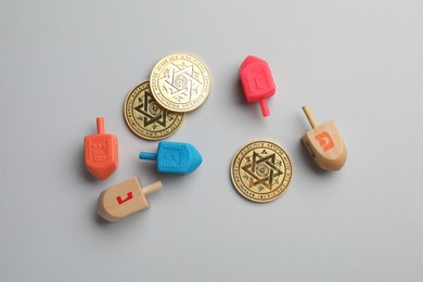 Photo of Dreidels with Jewish letters and coins on white background, flat lay. Traditional Hanukkah game