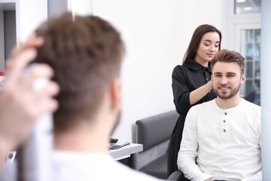 Photo of Professional female hairdresser working with client in salon