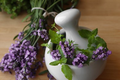 Photo of Mortar with fresh lavender flowers, mint and pestle on table, closeup