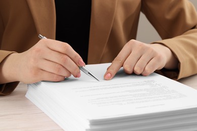 Woman signing document at wooden table, closeup