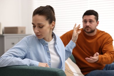 Photo of Tired wife stopping her husband indoors, selective focus. Relationship problems