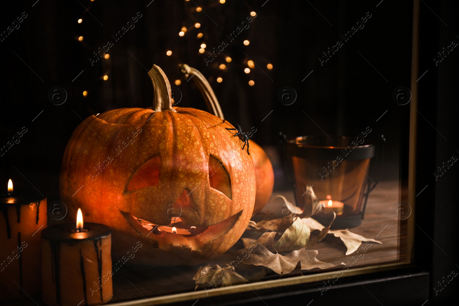 Photo of Composition with pumpkin head on windowsill, view through glass. Jack lantern - traditional Halloween decor