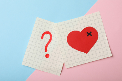 Paper notes with drawings of heart and question mark  on color background, flat lay. Relationship problems concept