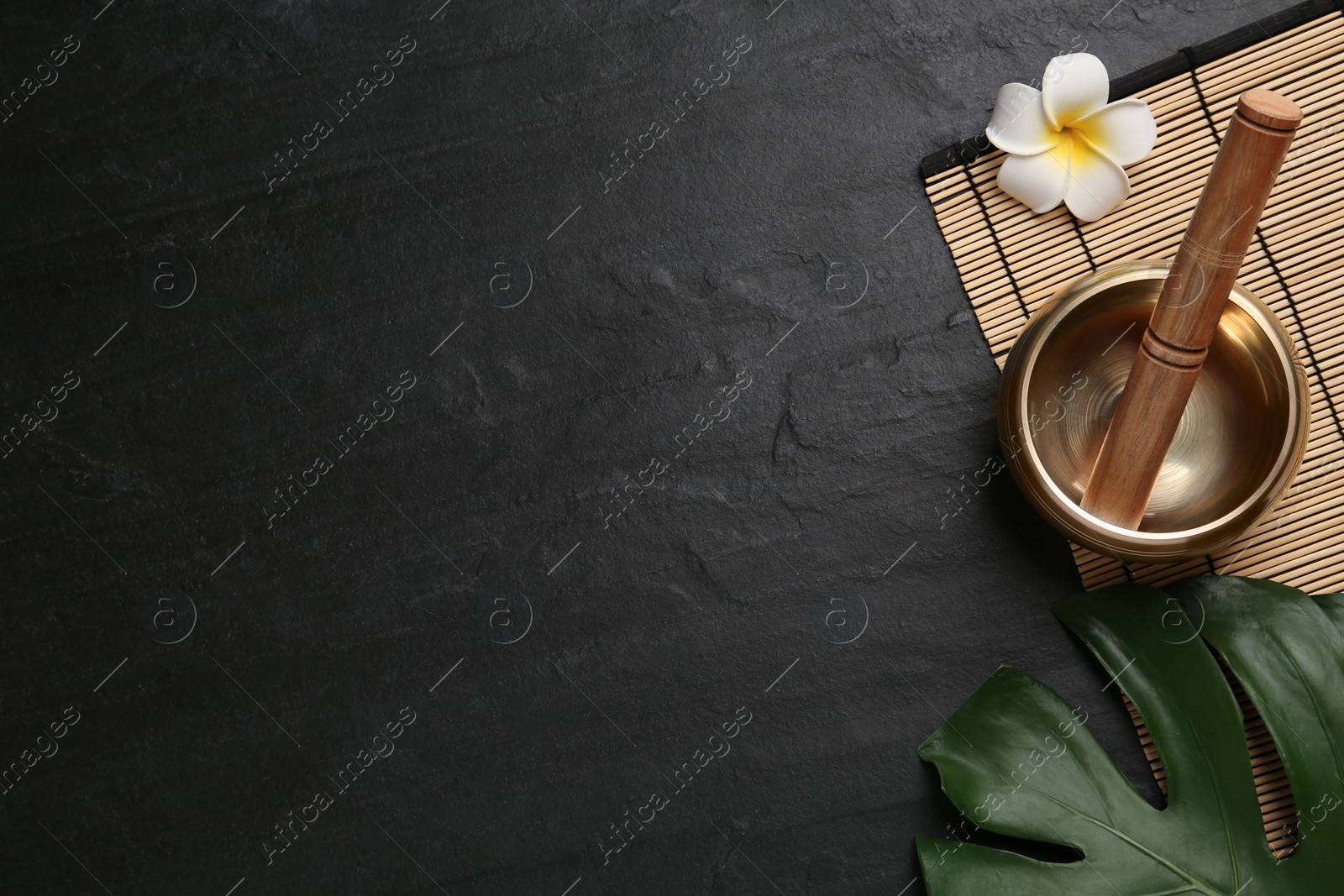 Photo of Flat lay composition with golden singing bowl on black table. Space for text