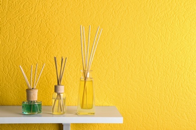 Photo of Reed air fresheners on table against yellow background, space for text