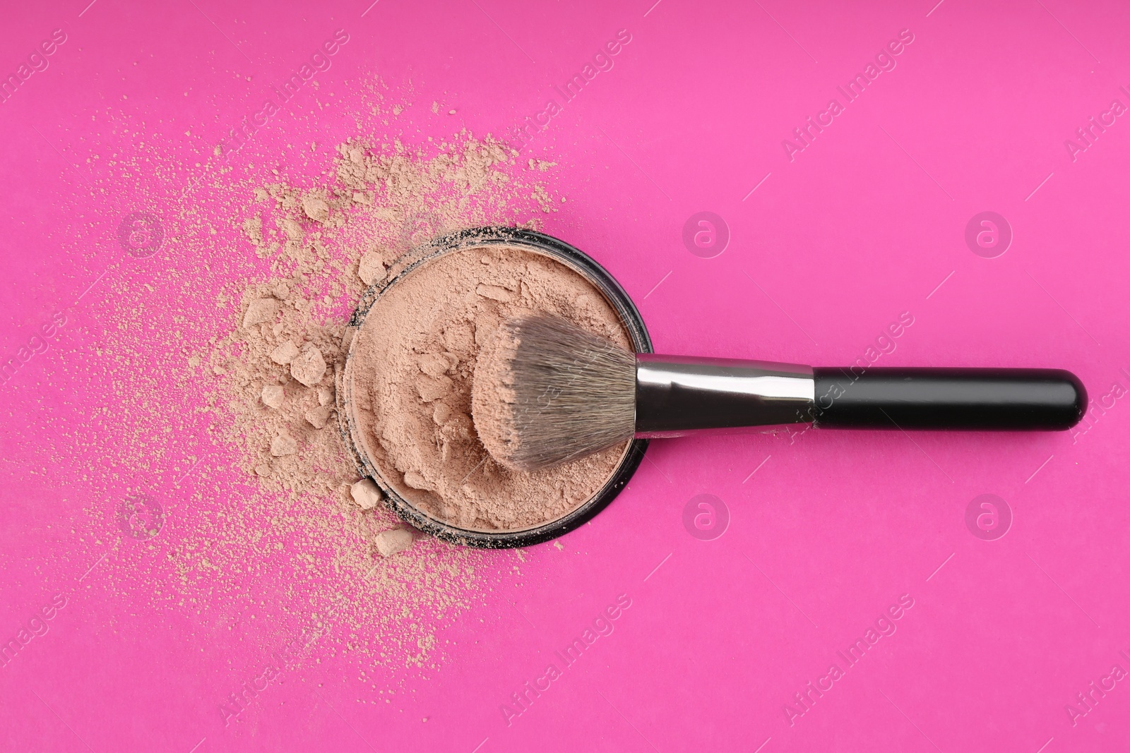 Photo of Makeup brush and face powder on bright pink background, flat lay