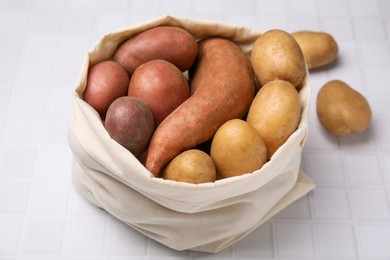 Photo of Different types of fresh potatoes in bag on white table