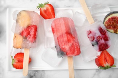 Flat lay composition with fruit and berry ice pops on light table