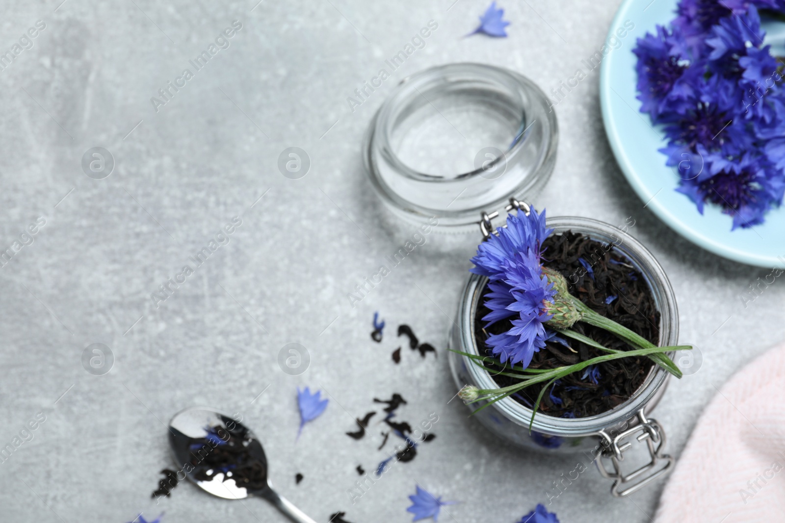 Photo of Flat lay composition with dry tea leaves and cornflowers on light table, space for text