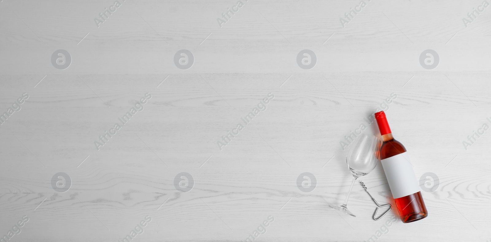 Photo of Flat lay composition with bottle of wine and elegant glass on white wooden background. Space for text