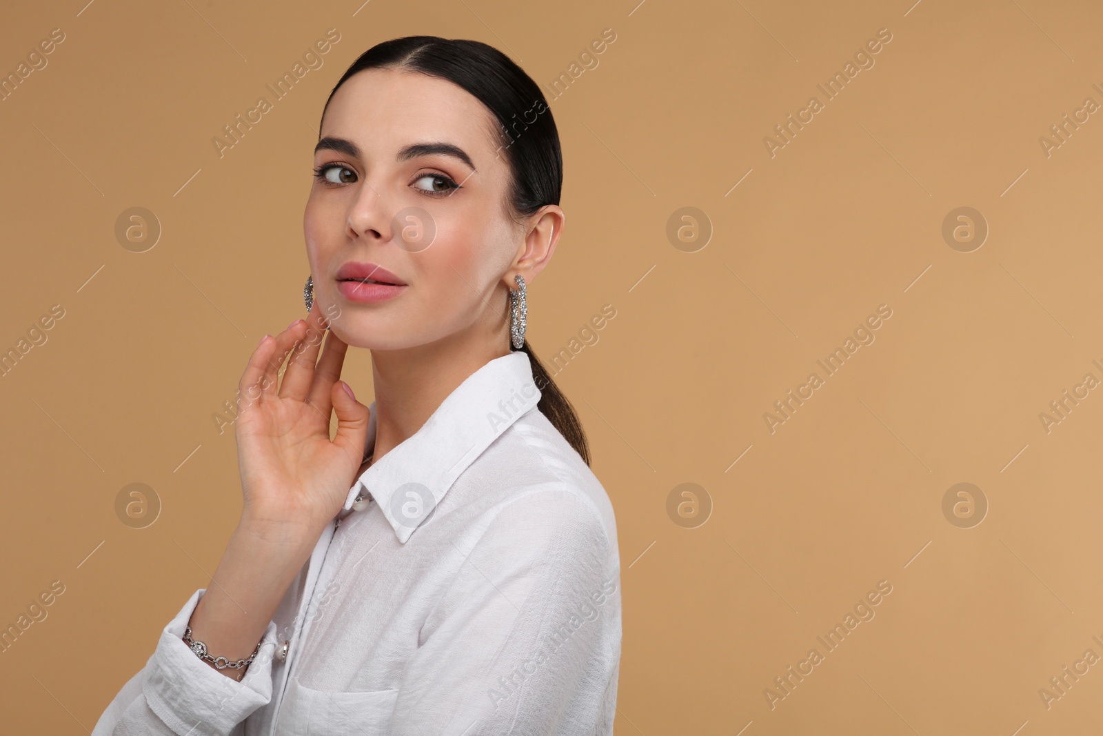 Photo of Beautiful young woman with elegant jewelry on beige background. Space for text