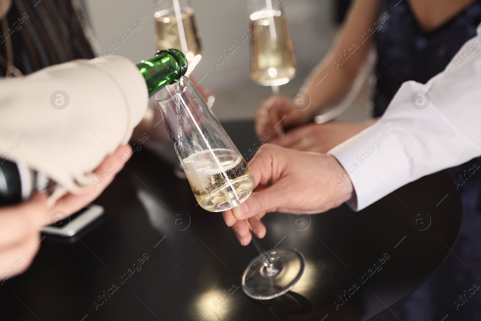 Photo of Waiter pouring champagne into man's glass at party, closeup