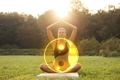 Beautiful woman meditating on mat in park. Yin and yang symbol