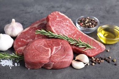 Raw beef steaks, oil and spices on grey table