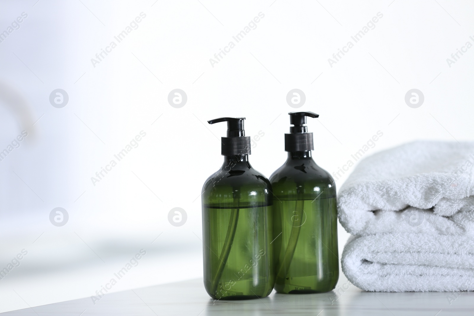 Photo of Soap dispensers and clean towels on white table. Space for text