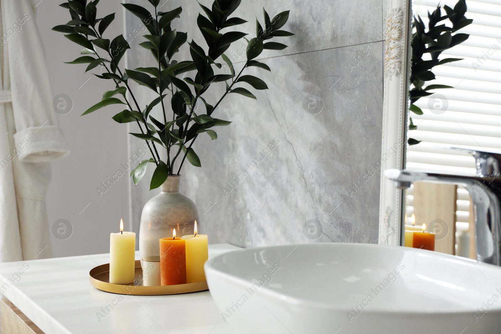 Photo of Beautiful plant in vase and burning candles near vessel sink on bathroom vanity