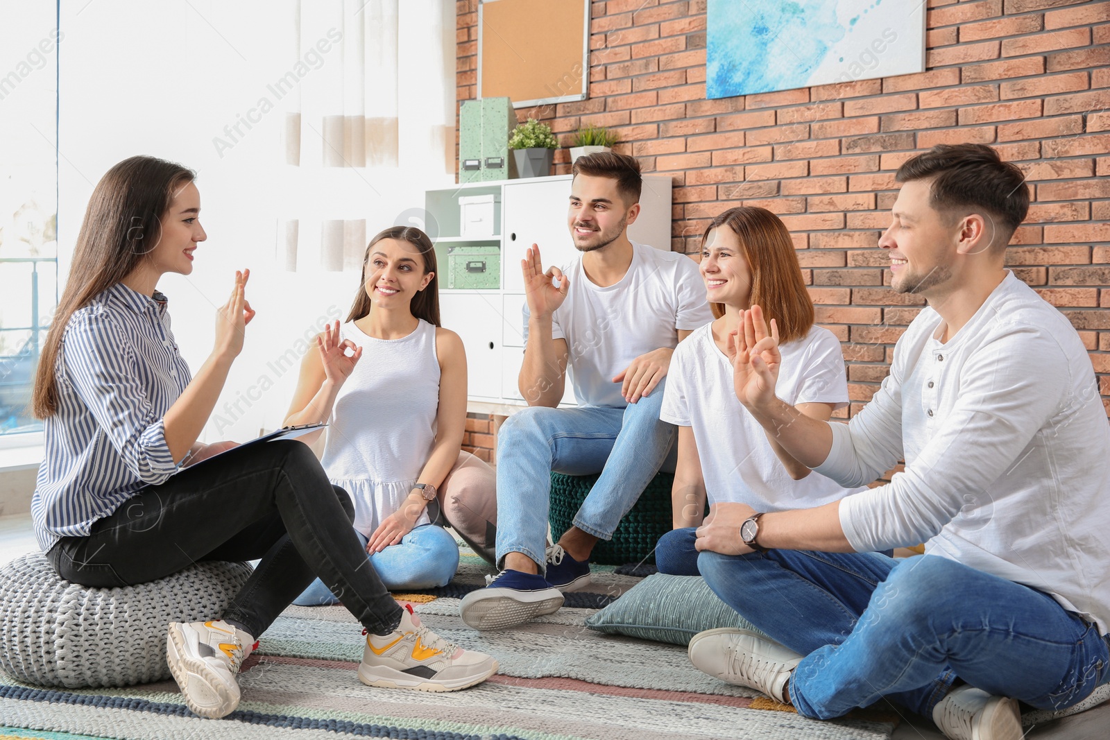 Photo of Group of young people learning sign language with teacher indoors