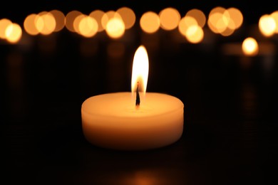 Photo of Burning candle on dark surface. Memory day