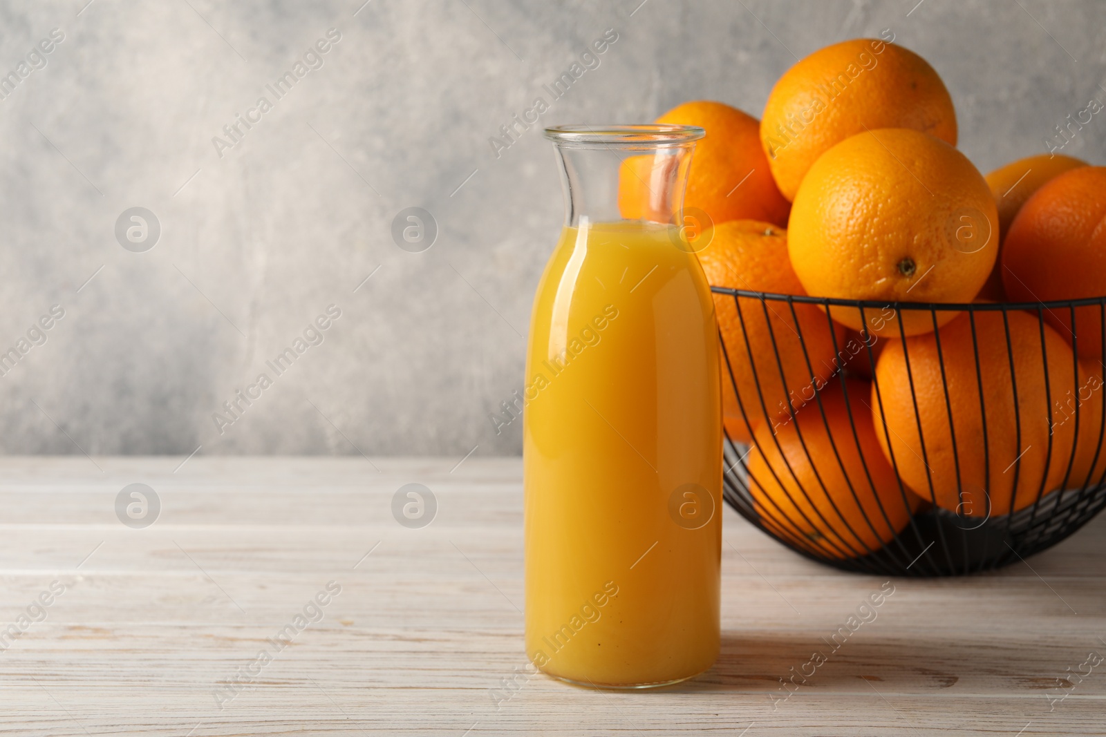 Photo of Tasty fresh oranges and juice in jug on white wooden table, space for text