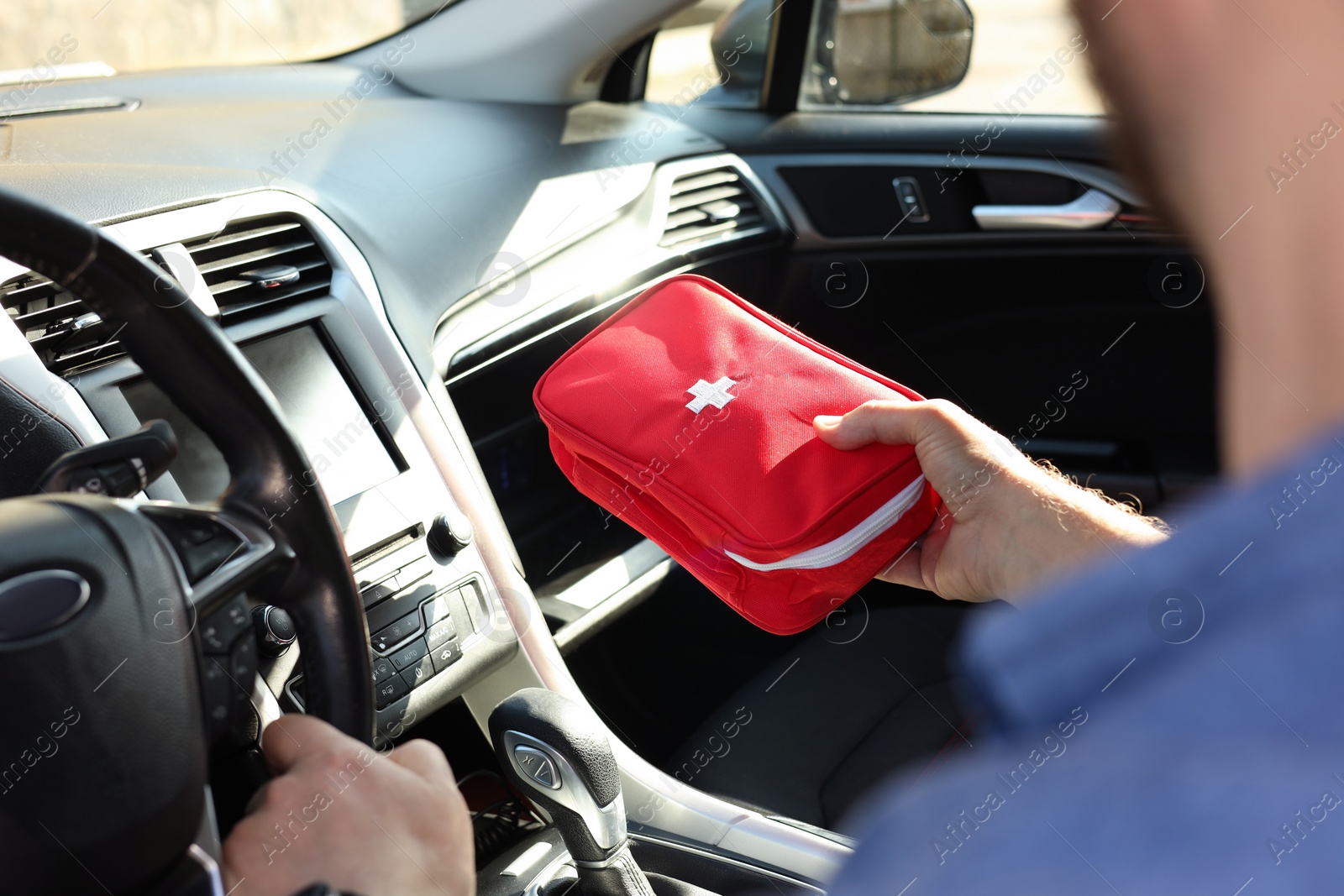 Photo of Man with first aid kit inside car, closeup