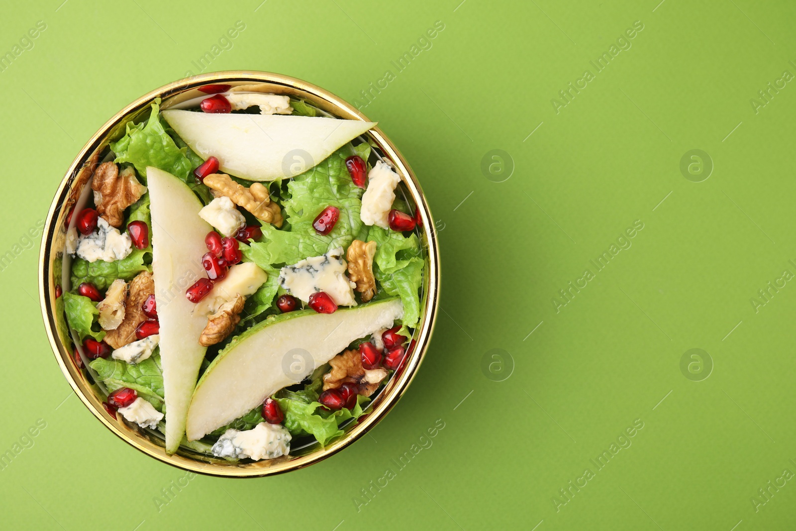 Photo of Delicious pear salad in bowl on green background, top view. Space for text