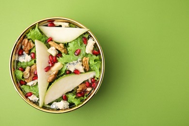 Delicious pear salad in bowl on green background, top view. Space for text